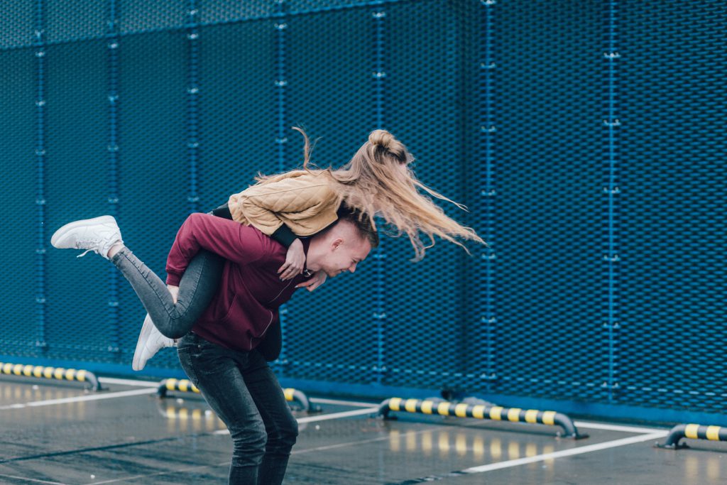 A young couple play around with the woman jumping on the man's back. A change in our own heart can help us improve our love relationships.